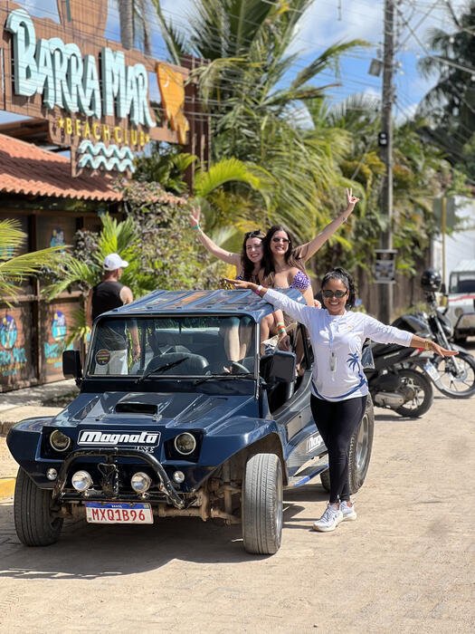 Grupo de amigos em cima de um buggy azul em frente à Barra Mar Beach Club